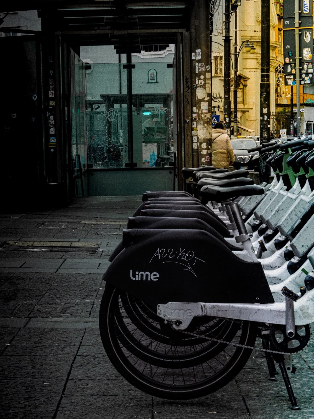 A row of shared bicycles parked along a graffiti-lined street.