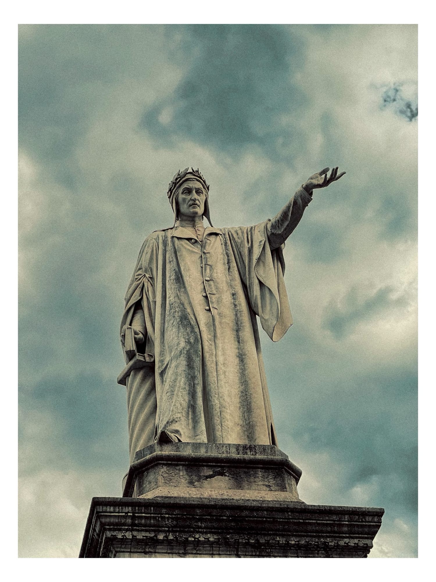 Marble statue of Dante Alighieri in Piazza Dante, one arm raised.