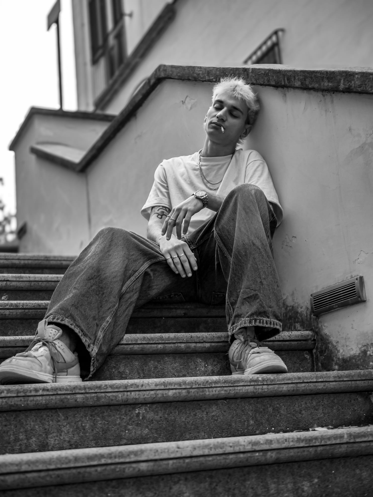 Black-and-white photo of Salar leaning on a wall, eyes closed, cigarette in hand.